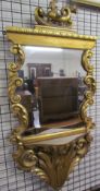 A gilt wall mirror with sea creature terminal scrolls and leaves