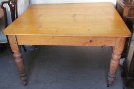 A scrub top pine kitchen table on four turned legs and casters