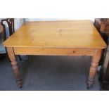 A scrub top pine kitchen table on four turned legs and casters
