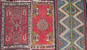 A small red ground rug, decorated with flowers and leaves,