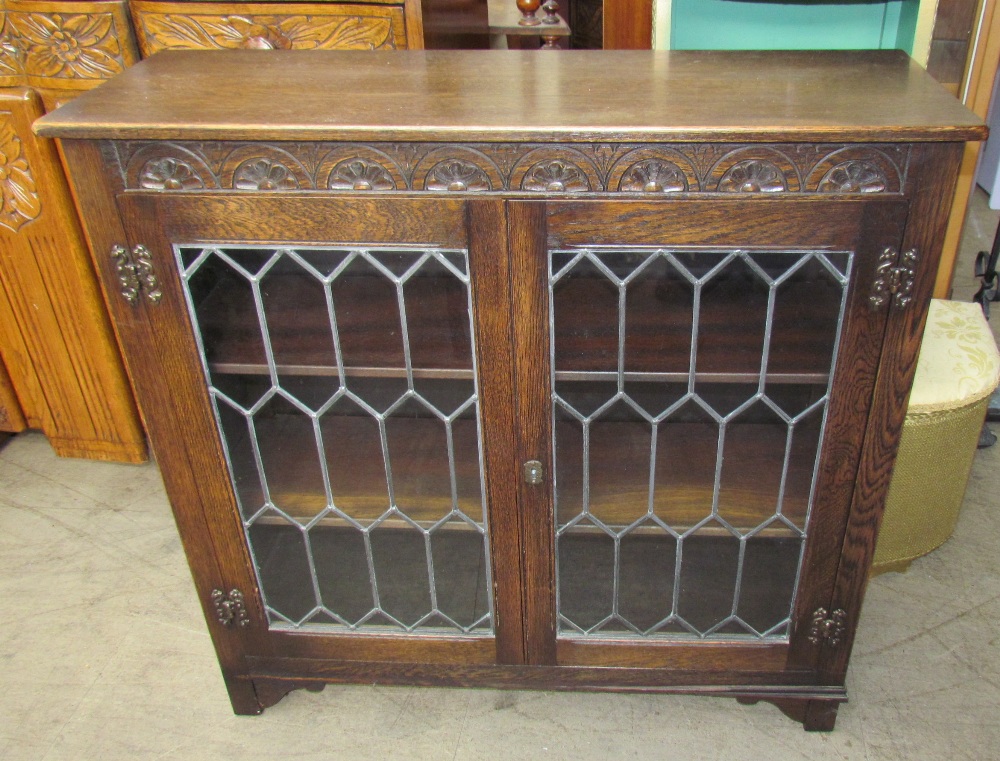 A 20th century oak bookcase with a carved cornice and leaded glazed doors