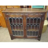 A 20th century oak bookcase with a carved cornice and leaded glazed doors