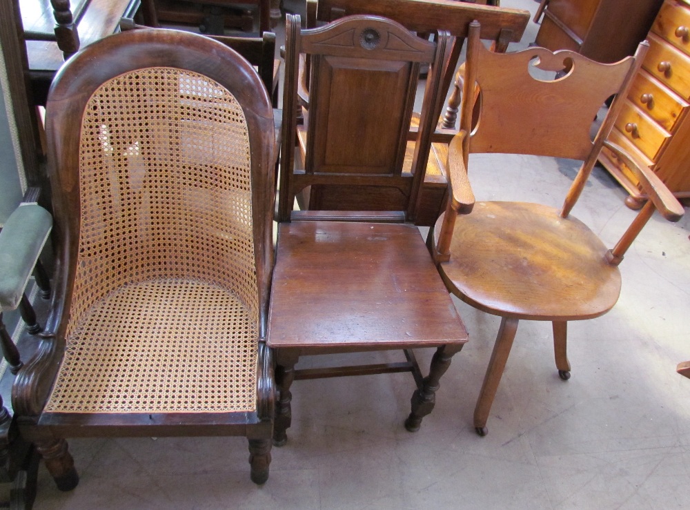 An early 19th century bergère nursing chair together with an office chair and a dining chair