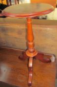 A mahogany wine table with a circular top and baluster column on three legs