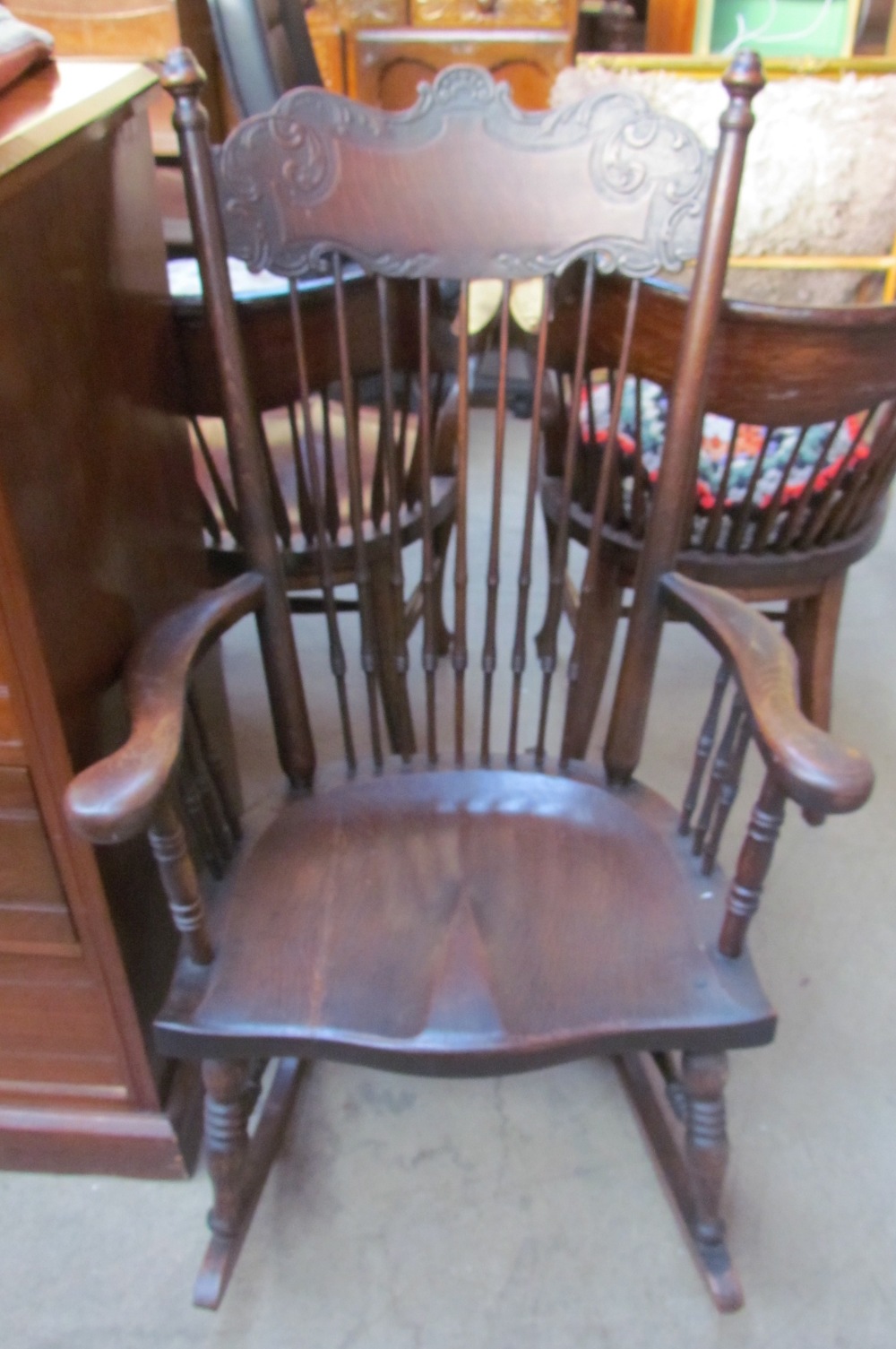 An oak stick back rocking chair with a solid seat on ring turned legs and rocker base