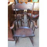 An oak stick back rocking chair with a solid seat on ring turned legs and rocker base