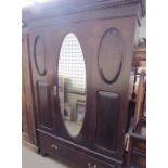 An Edwardian mahogany wardrobe with a single mirrored door and base drawer