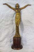 An Art Deco style gilt decorated figure of a maiden with outstretched arms on a wooden base