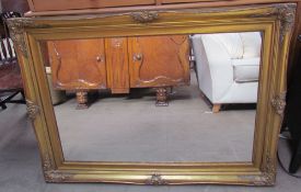 A large gilt wall mirror with a leaf cast border