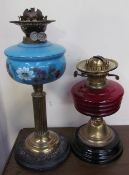 A Victorian oil lamp with a cranberry glass reservoir together with another with a blue glass