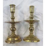 A 17th century style brass candlestick with central drip pan on a spreading foot,