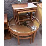 A light teak coffee table with a glass top and a set of three pointed oval occasional tables,