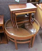 A light teak coffee table with a glass top and a set of three pointed oval occasional tables,