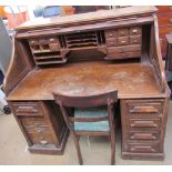 An oak roll top desk with a serpentine tambour top,