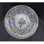 A Majolica charger, painted to the edge with flowerheads and leaves, the centre painted with fruit,