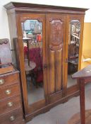 An Edwardian walnut triple wardrobe with a moulded cornice above three doors on a plinth base