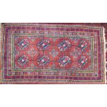 A Turkoman rug with a light red ground and eight geometric medallions and multi coloured guard