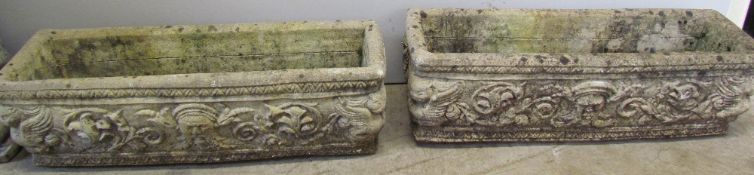 A pair of reconstituted stone planters cast with masks and leaves