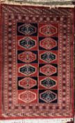 A rug with a red and blue panelled ground with twelve guls and multiple guard stripes,