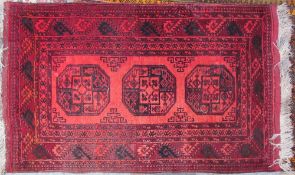 A red ground rug with three central medallions to multiple guard stripes,