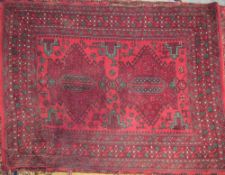 A rug with a red ground and two medallions with hooked botehs and multiple guard stripes,