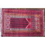 A red ground prayer rug with a central mihrab and multiple guard stripes,