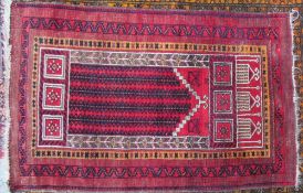 A red ground prayer rug with a central mihrab and multiple guard stripes,
