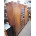 A 20th century walnut wardrobe with central glazed door and drawers flanked by a pair of cupboard