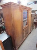 A 20th century walnut wardrobe with central glazed door and drawers flanked by a pair of cupboard