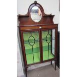 An Edwardian mahogany display cabinet with an oval mirrored back on square tapering legs and spade