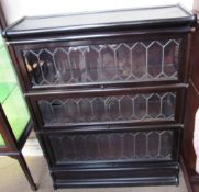 A sectional bookcase with three leaded glass doors on a plinth