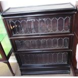 A sectional bookcase with three leaded glass doors on a plinth