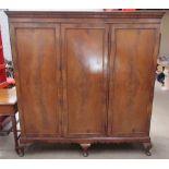 A walnut triple wardrobe with a moulded cornice and three drawers enclosing linen slides,