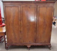 A walnut triple wardrobe with a moulded cornice and three drawers enclosing linen slides,