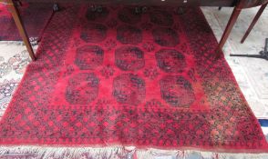 A large red ground rug with eighteen geometric guls and broad guard stripes