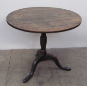 A 19th century oak tripod table with a planked top and baluster column on a tripod base