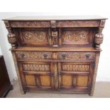 A 17th century style oak court cupboard with a carved frieze drawer above a pair of cupboard doors