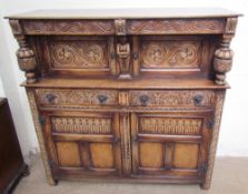 A 17th century style oak court cupboard with a carved frieze drawer above a pair of cupboard doors