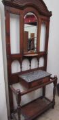 An Edwardian oak hall stand with a central mirror shelf, hook,