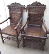 A matched pair of oak elbow chairs with carved panels and solid seats on turned legs