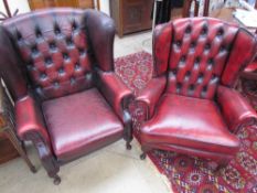 A pair of red leather wing back elbow chairs