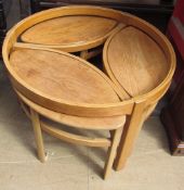 A light teak coffee table of circular form with three oval tables underneath,