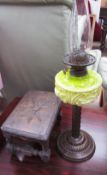 A Victorian oil lamp with a lime green glass reservoir and a metal column and base together with a