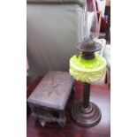 A Victorian oil lamp with a lime green glass reservoir and a metal column and base together with a