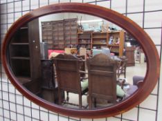 An oval wall mirror with cross banding and stringing