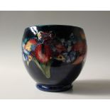 A Moorcroft pottery vase, decorated in the orchid pattern to a royal blue ground,