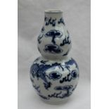 A Chinese porcelain double gourd vase decorated with dragons chasing a pearl, with clouds above,