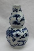 A Chinese porcelain double gourd vase decorated with dragons chasing a pearl, with clouds above,