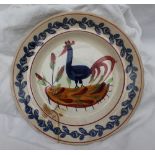 A Llanelly pottery cockerel plate, with a red line border and floral sponge decorated rim,