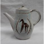 A studio pottery coffee pot, with a white glaze and decorated with stylised horses in browns,